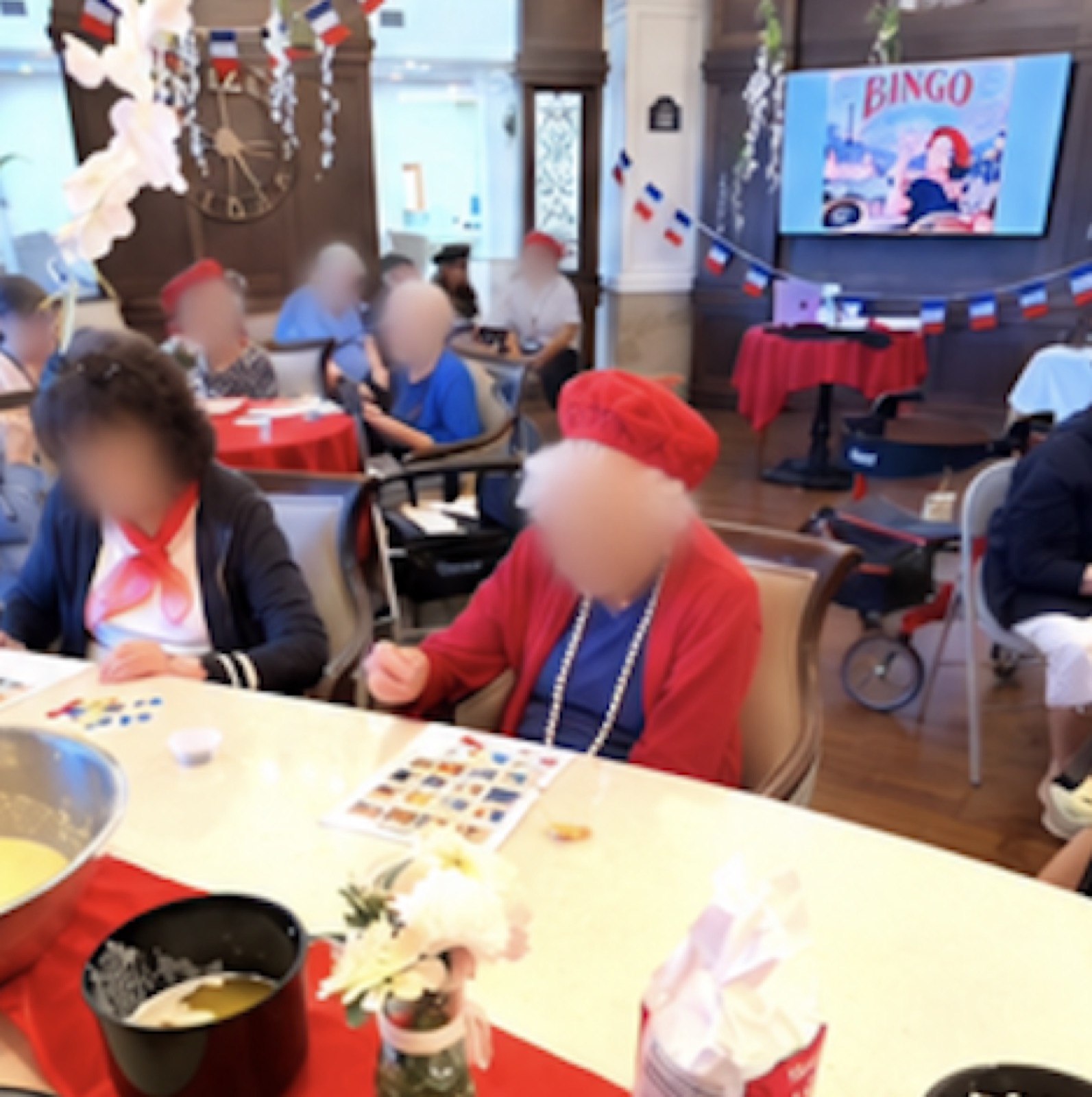 Residents at a table with a French bingo card, flags, and a screen behind them.