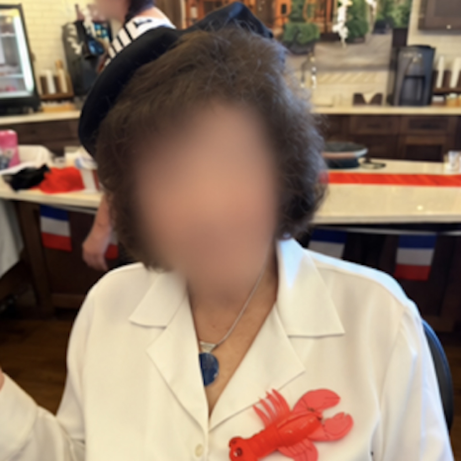 A resident in a white jacket with a lobster pin and a French flag in the background.