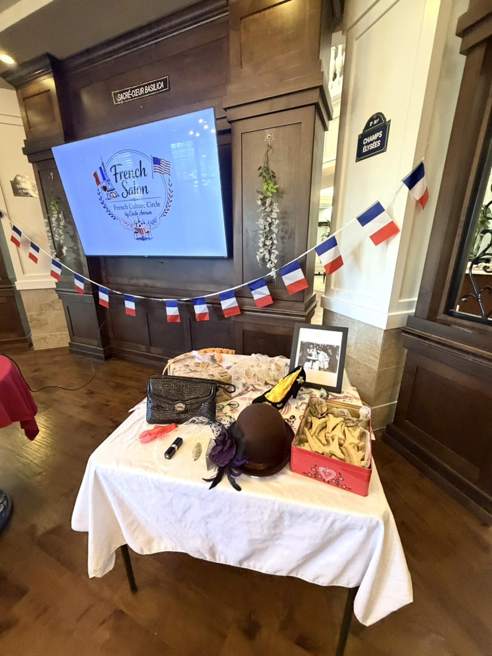 A French Salon table set beneath a screen reading French Salon, with French flags and street signs for Sacré-Cœur and the Champs-Élysées.