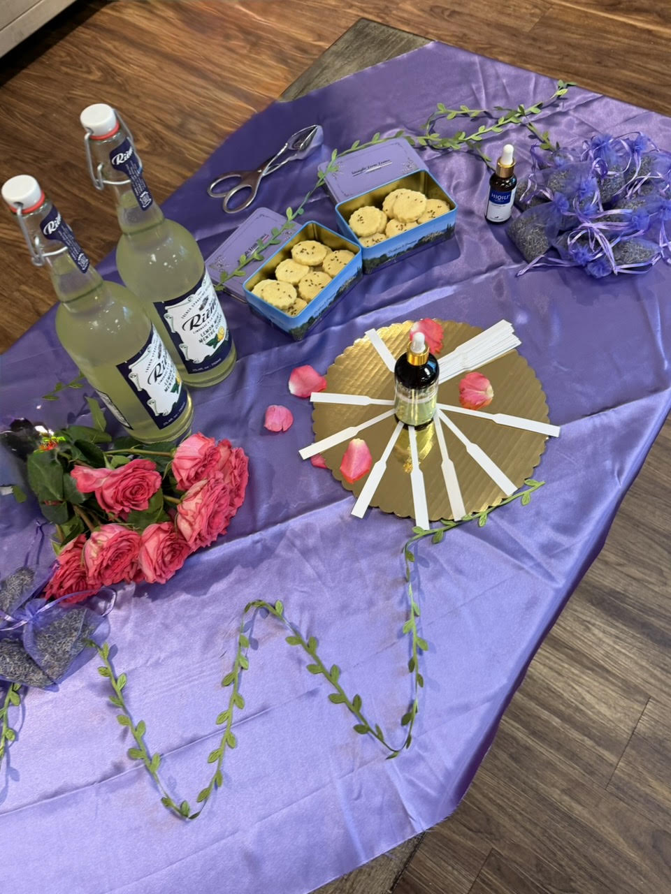A lavender cloth arranged with roses, lemonade, shortbread, and perfume blotters for a Provence session.